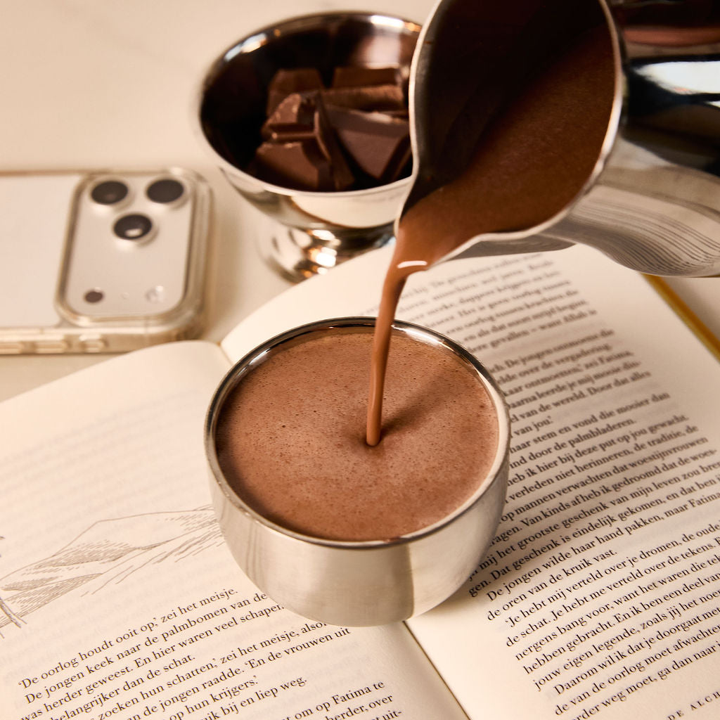 Ceremonial cacao poured into a cup during a calm morning ritual with a book